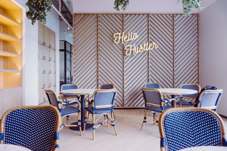 Café-style lounge with neon Hello Hustler sign and blue bistro chairs